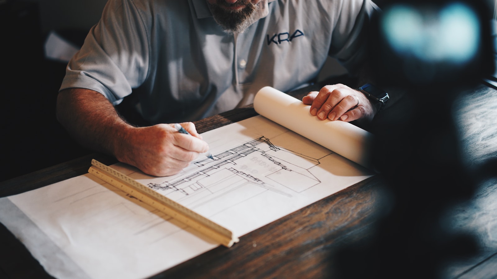 An architect hand-drafting a construction detail with a ruler and pencil